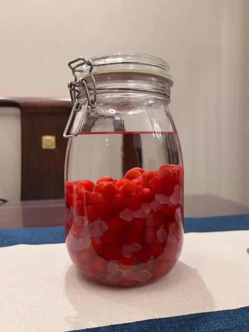 家庭自酿樱桃泡酒成品展示：透明玻璃罐中装着色泽诱人的樱桃酒_1