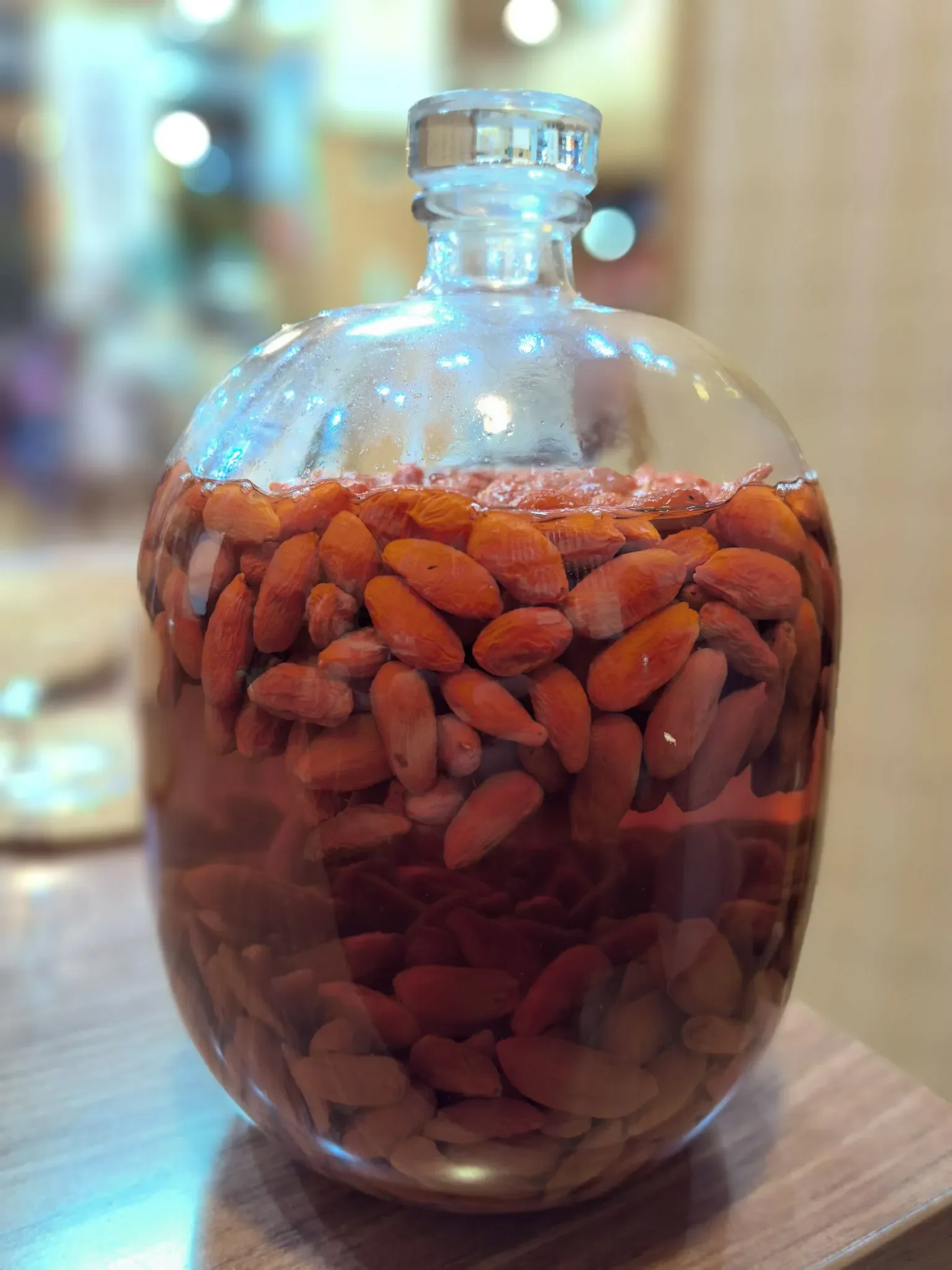 广口玻璃罐中正在泡制的补肾果酒特写，酒液琥珀色，果实饱满，旁边散落着枸杞等辅料。_1