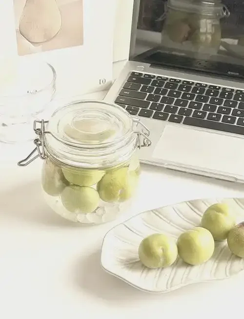 李子酒发酵过程特写：玻璃罐中李子与酒液正在发酵冒泡，旁边放置着准备过滤的干净容器和滤网。_1