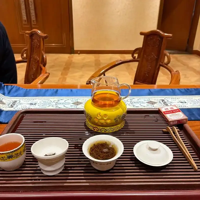 温热的茶汤从茶壶倒入白瓷茶杯，旁边放着一小杯白酒，画面宁静舒缓。_1