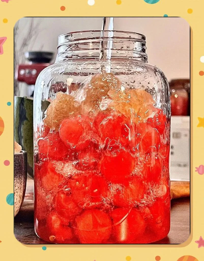 西瓜酿酒过程：透明发酵罐中的粉红色西瓜汁正在发酵，旁边是新鲜切开的西瓜和酿酒工具。_1