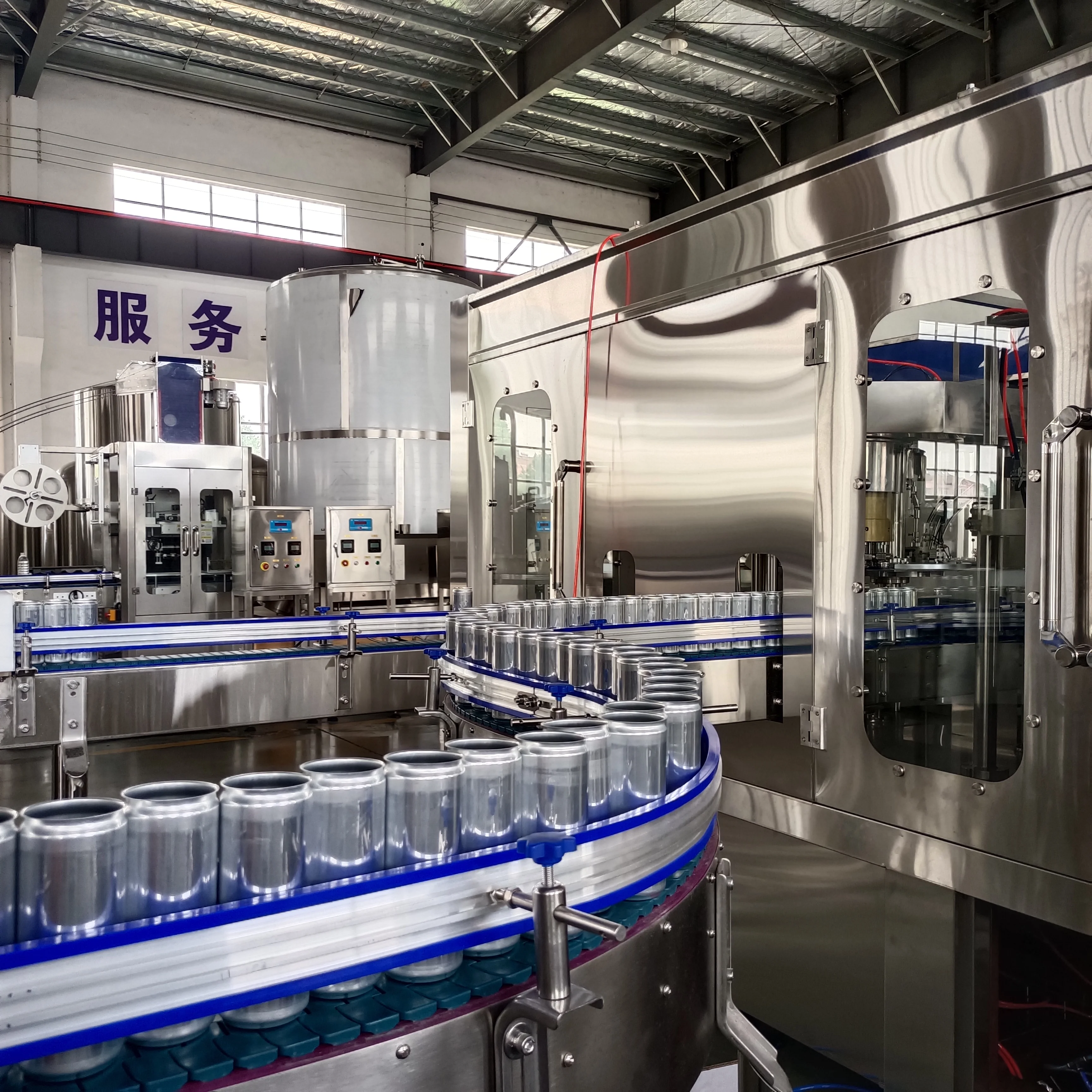 小型啤酒灌装生产线车间工作实景：灌装机、压盖机与传送带协同运作，酿酒师在旁检查。_1