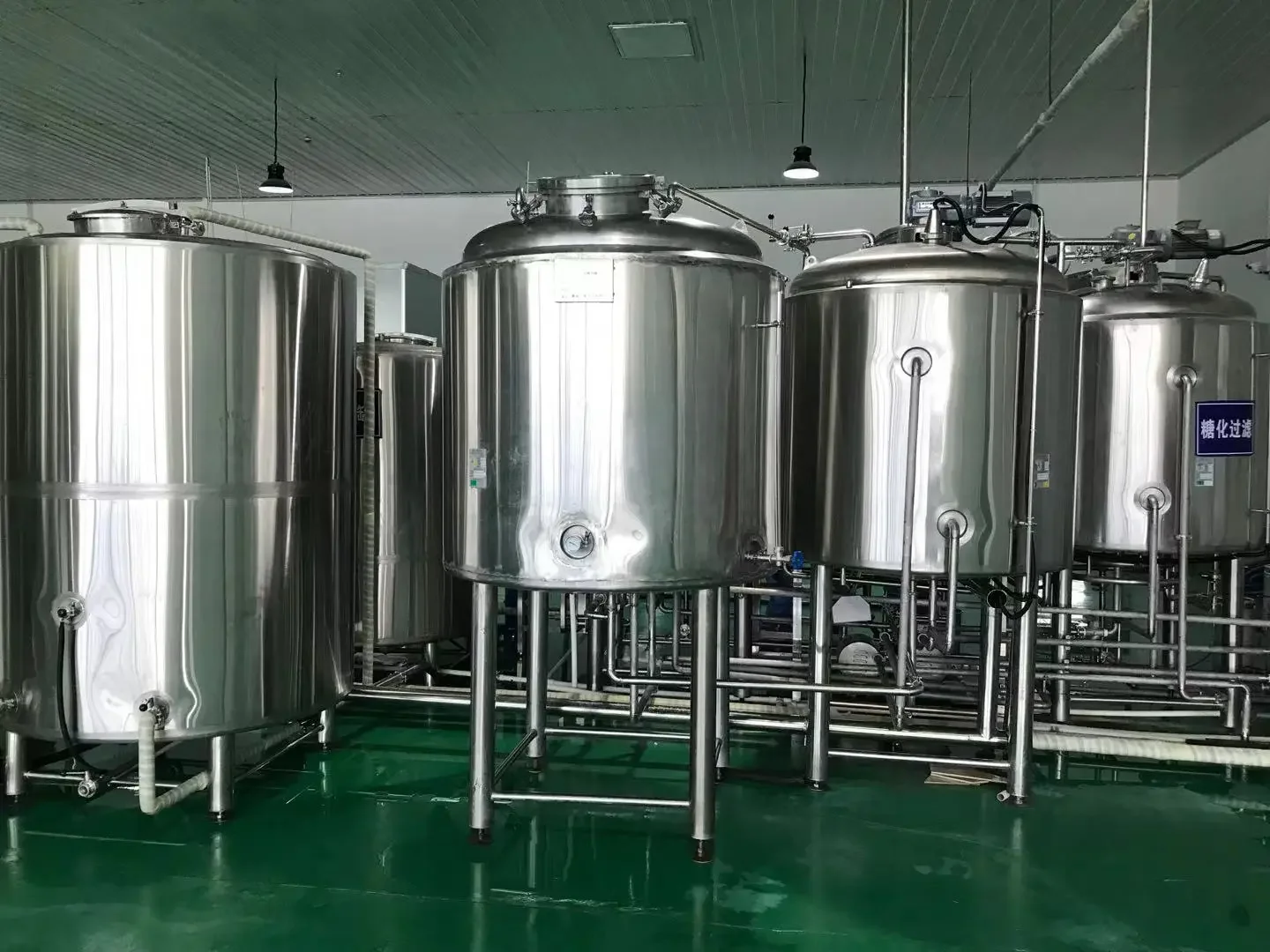 小型精酿啤酒作坊内部，酿酒师正在操作不锈钢酿造设备_1