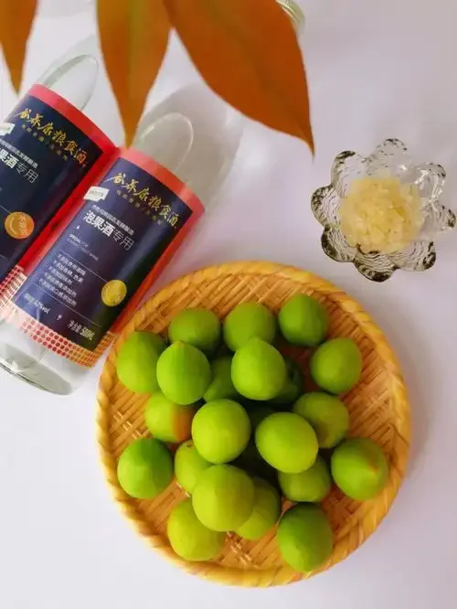 自制青梅酒成品展示：透明玻璃罐中琥珀色酒液浸润着饱满的青梅与黄冰糖，阳光照射下显得格外诱人。_1