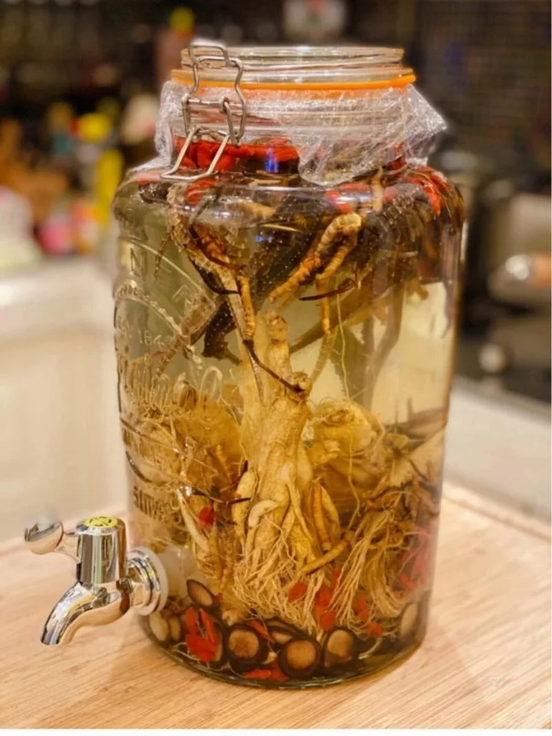 一瓶正在浸泡中的家庭自制补肾药酒特写，玻璃罐内清晰可见人参、枸杞等中药材，色泽琥珀，氛围温馨专业。_1