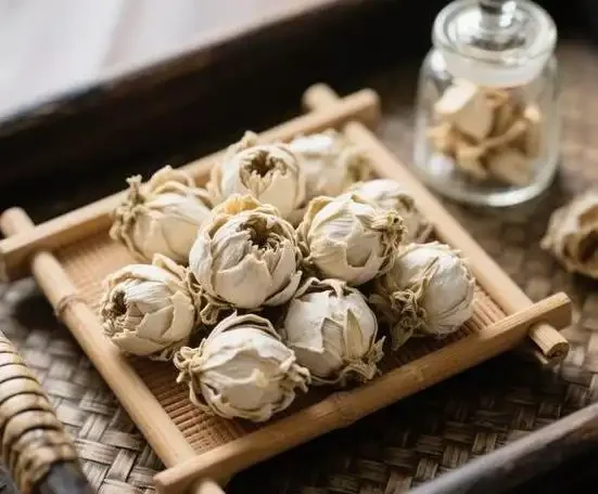 透明玻璃罐中雪莲花与鹿茸、枸杞、当归等中药材在琥珀色酒液中浸泡的特写，展示雪莲祛风湿药酒的经典配伍。_1
