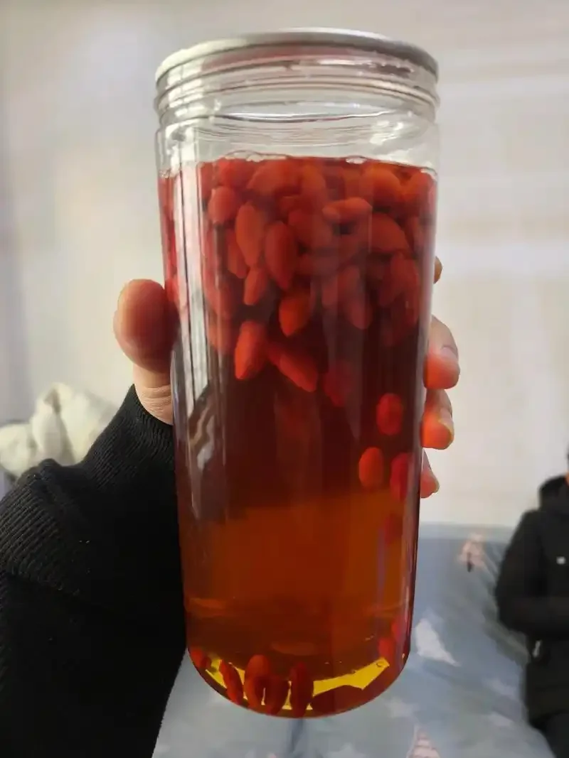 海马枸杞玛卡泡酒实物展示：透明酒罐中清晰可见药材与琥珀色酒液_1