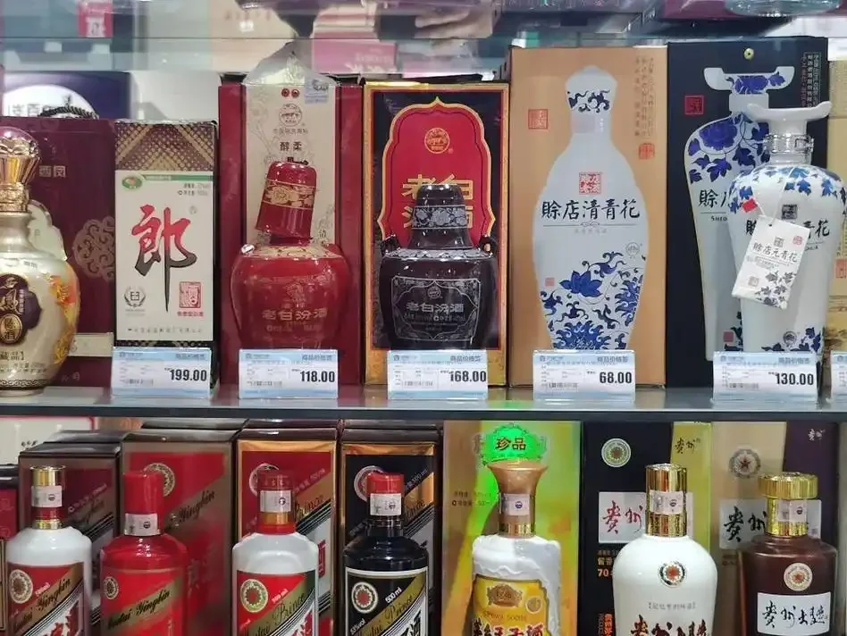 超市货架上几款平价白酒的瓶身特写，可以清晰看到标签上的执行标准号和配料表。_1
