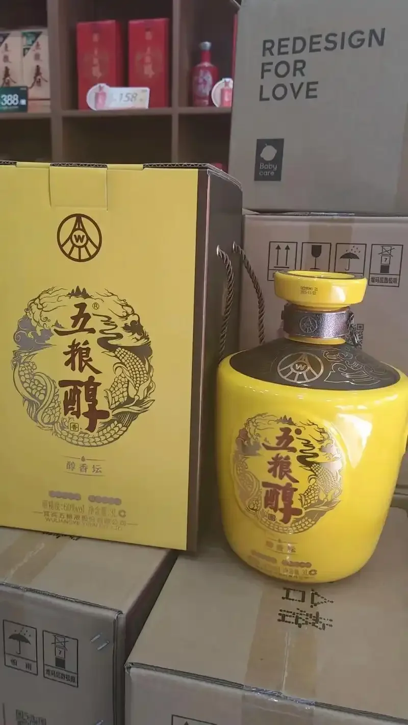 酿酒师在车间里从酒坛中舀出新酒，旁边堆放着准备酿酒的高粱粮食_1