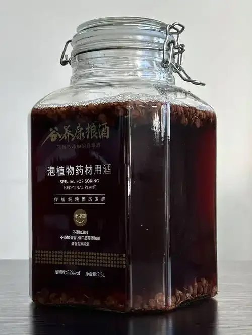 一瓶家庭自制的桑葚干泡酒特写，酒液呈深红色，桑葚干沉淀在瓶底，旁边散落着新鲜和风干的桑葚，整体氛围温馨专业。_1