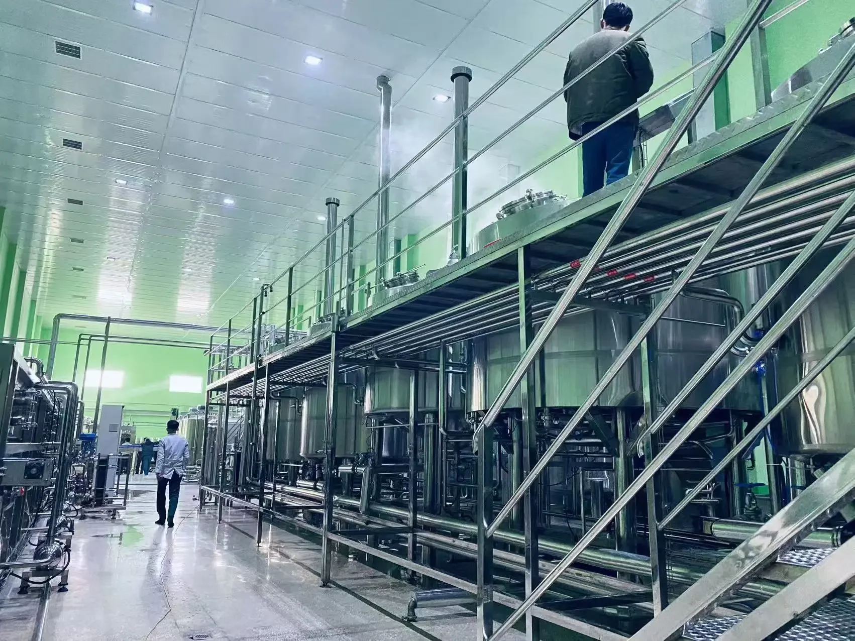 精酿啤酒工坊内，酿酒师正在操作一套中型不锈钢糖化煮沸设备，检查酿造过程。_1