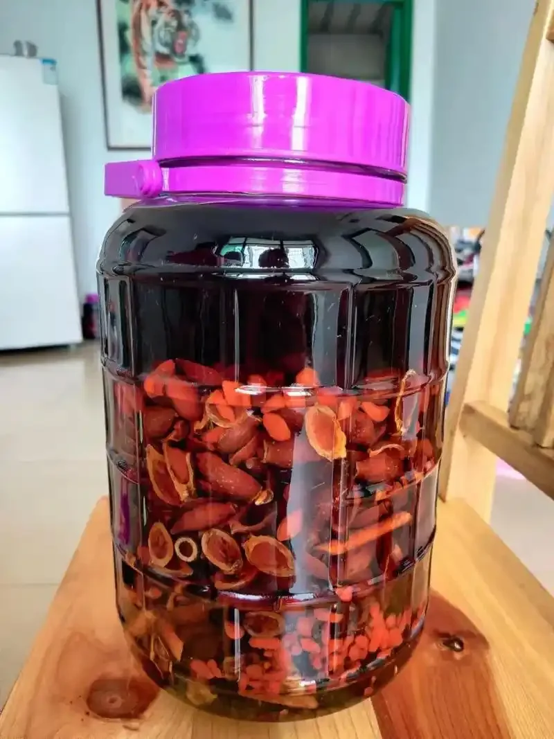 金樱子泡酒成品特写,玻璃罐中可见金樱子、枸杞等材料,旁边有新鲜果实和秤,展示泡酒过程。_1