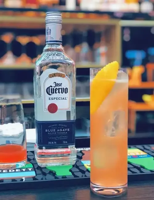 一杯经典帕洛玛鸡尾酒的特写，配有龙舌兰酒、新鲜西柚、青柠和苏打水等原材料，展示了家庭调酒的场景。_1