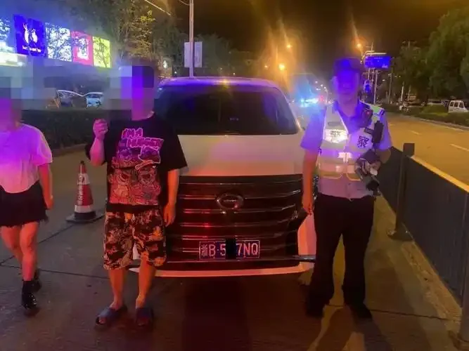 交警在进行酒精检测，驾驶员面露懊悔，背景为深夜路口警灯闪烁。_1