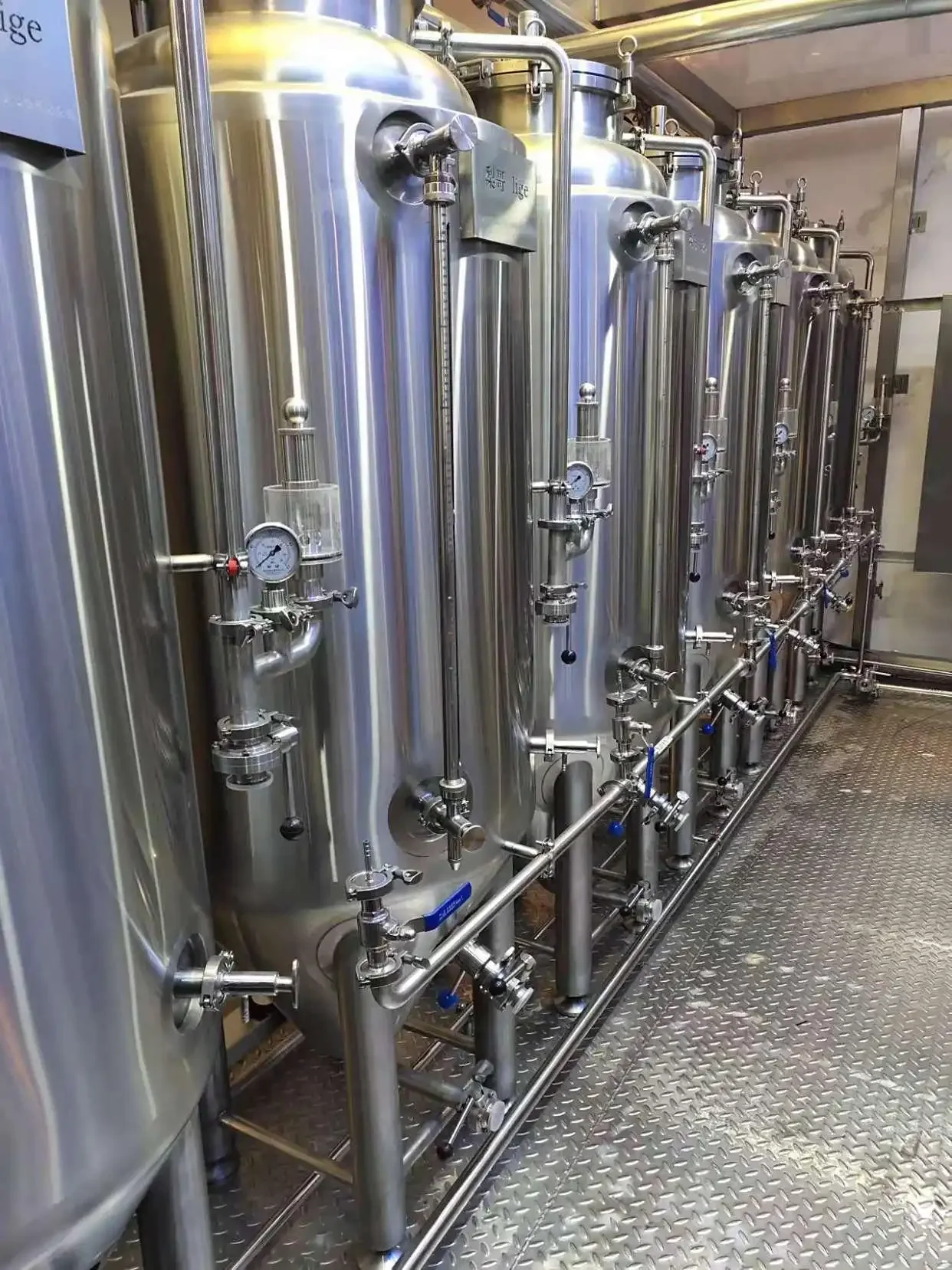一套正在工作的不锈钢精酿啤酒设备，旁边摆放着麦芽原料，展现了小型精酿坊的核心酿造场景。_1