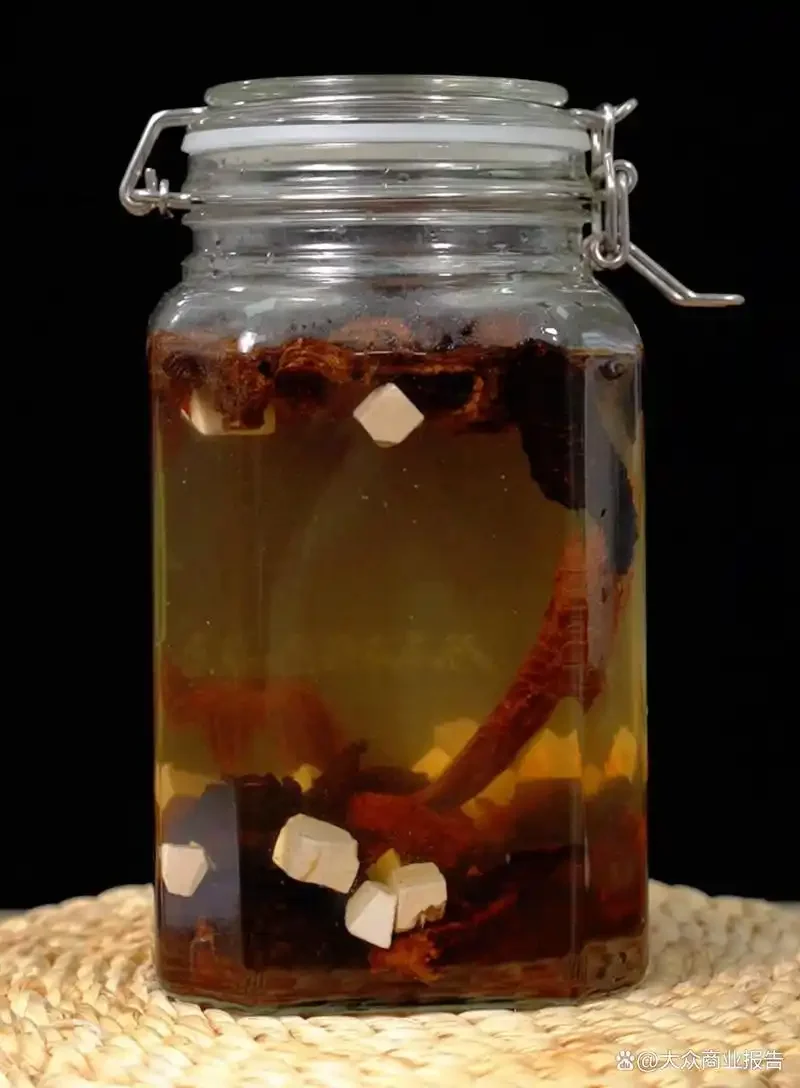透明玻璃坛中浸泡的肉苁蓉海马酒特写，酒液呈琥珀色，可见海马与肉苁蓉片细节。_1