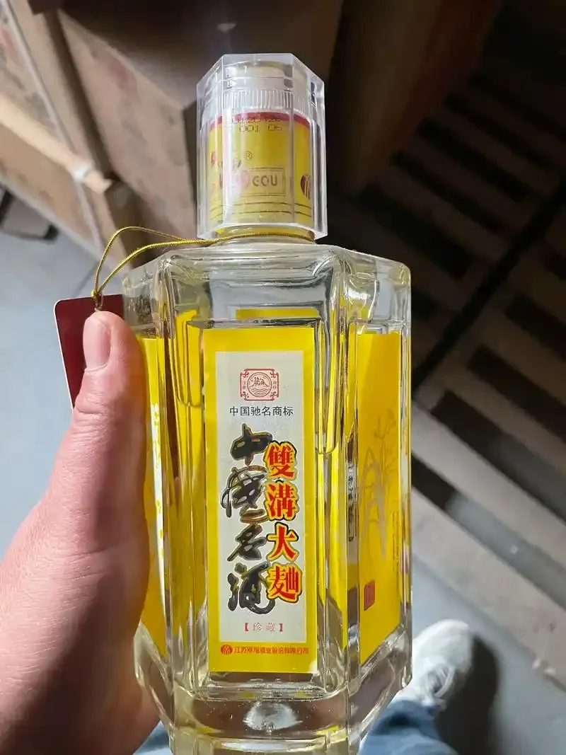 一瓶双沟大曲酒与背后传统的双沟酒厂生产车间及窖池景观，展现名酒的生产环境。_1