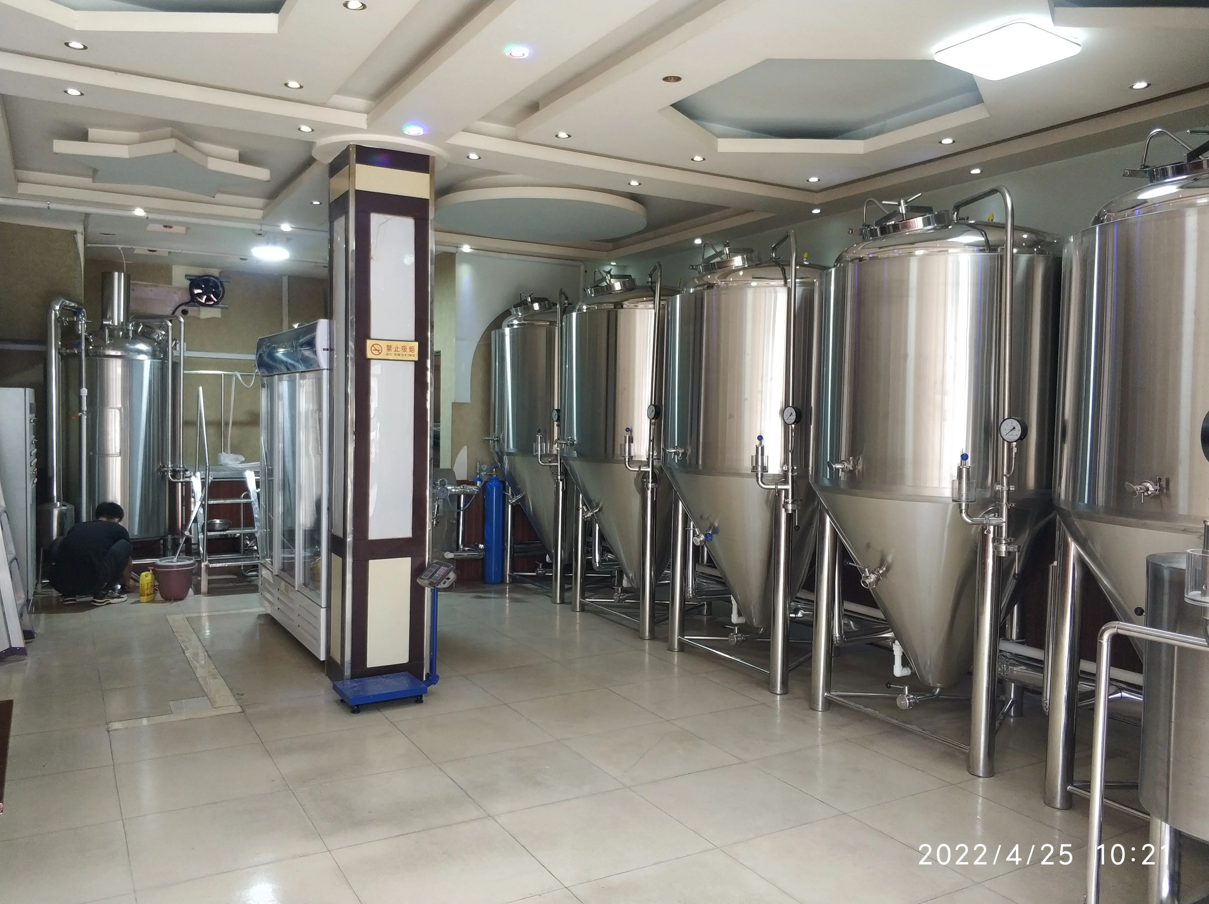 家庭果酒发酵设备实景：玻璃发酵罐中的桑葚酒正在冒泡，配有水封装置，旁边摆放着原料和工具。_1