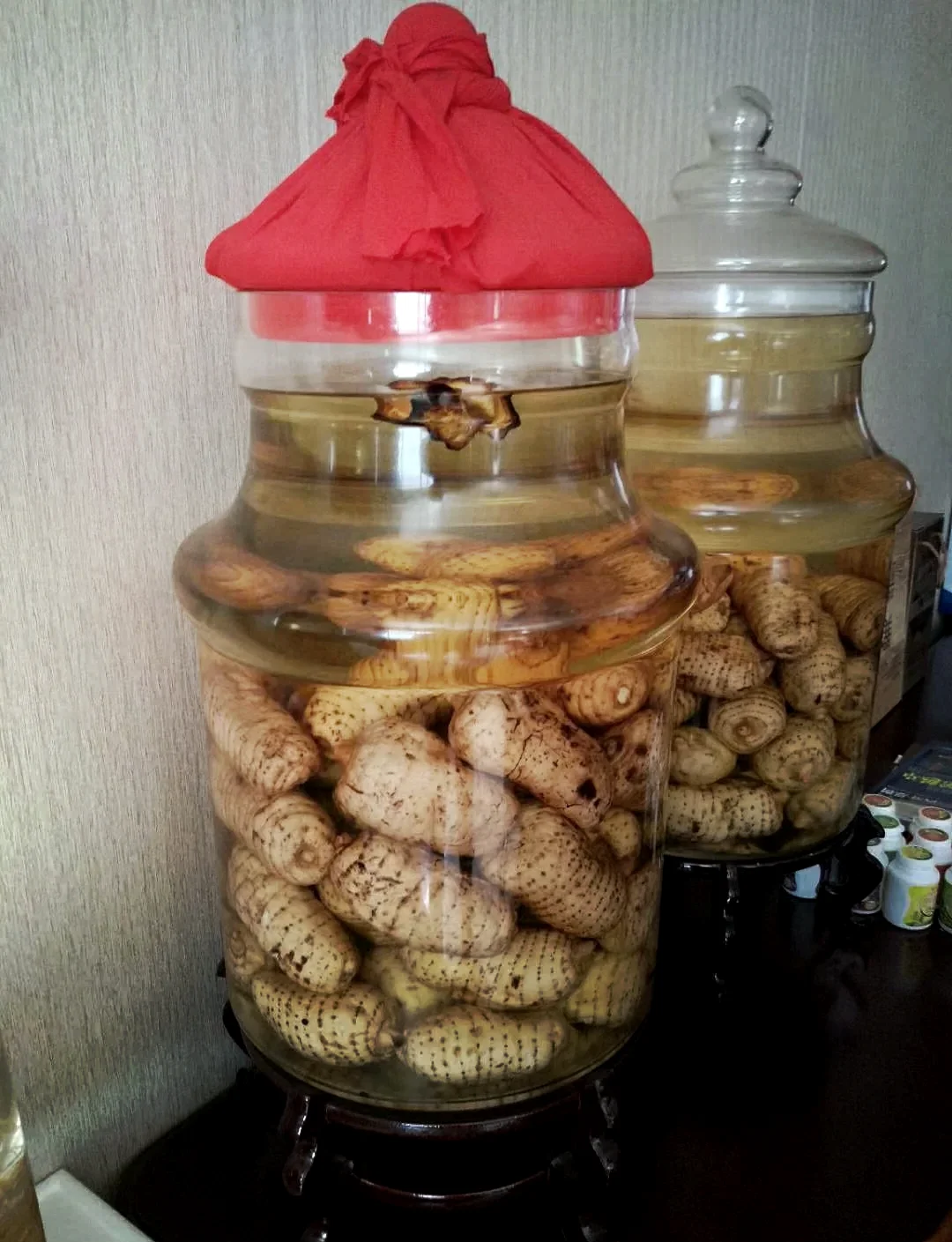 一瓶已存放三年的天麻泡酒特写，酒液呈深琥珀色，瓶底有沉淀，旁边放着空酒杯用于对比观察。_1