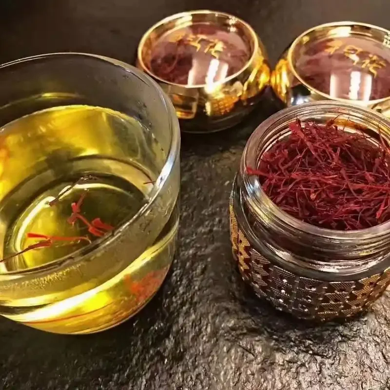 藏红花泡酒材料与成品展示：玻璃瓶中金黄色的酒液浸泡着藏红花、枸杞和红枣，旁边散落着原材料和笔记本。_1