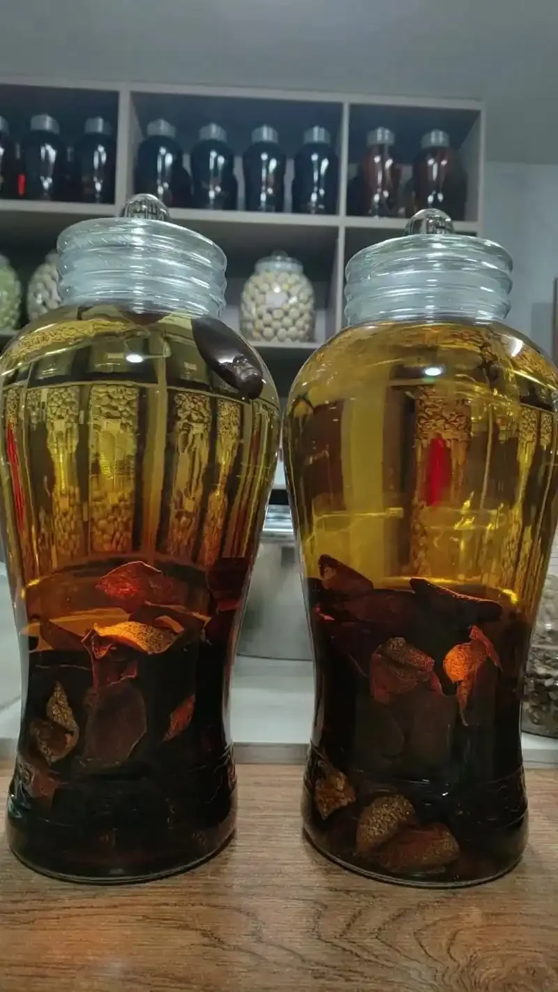 用于祛风湿的药酒坛与精选中药材（当归、川芎、牛膝等）摆放在木质桌面上的俯拍图_1