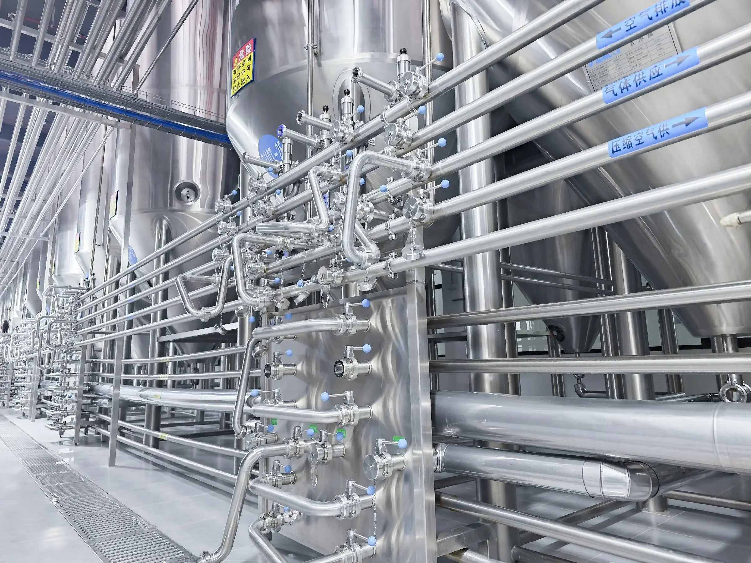 一套专业不锈钢精酿啤酒设备特写，包括煮沸锅和发酵罐，背景是摆满啤酒的酒架，展现家庭或小型酒坊的酿造场景。_1