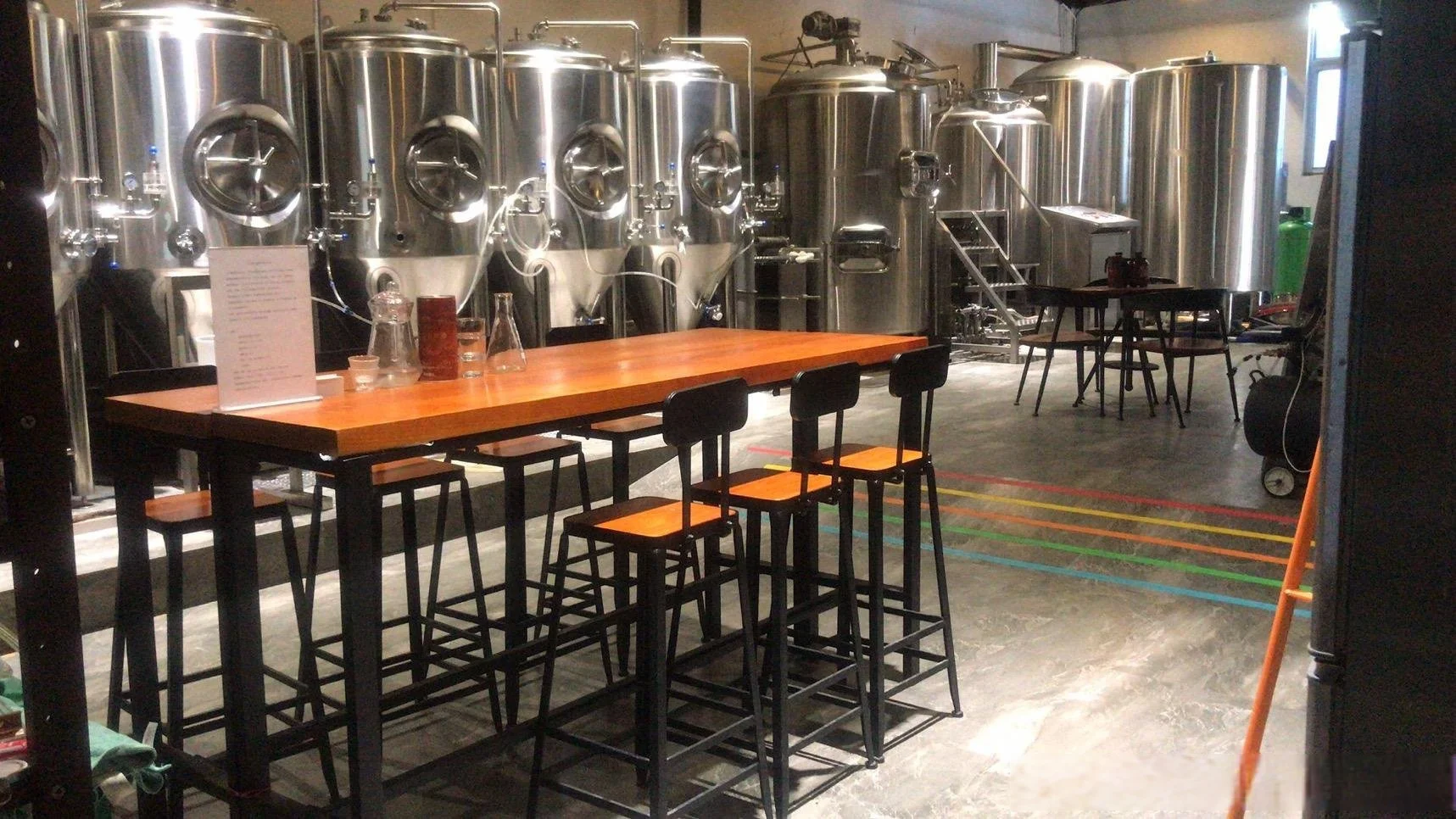 酿酒师正在工作室中操作一套不锈钢小型精酿啤酒设备，背景可见各种酿造原料。_1