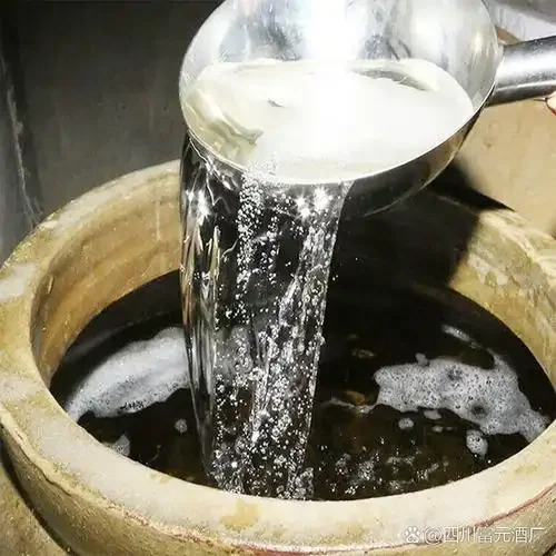 酿酒师在传统酒坊中展示新鲜酿出的粮食酒液_1