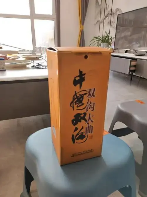 资深酿酒师在酒坊中手持一瓶实惠的纯粮酒进行讲解，背景是传统酿酒工具。_1