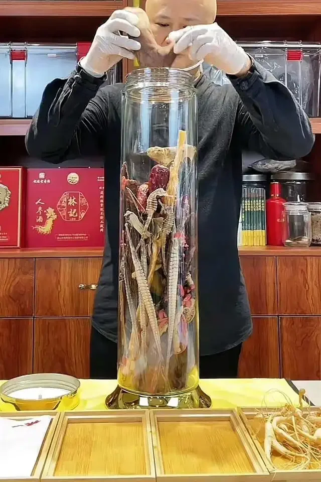 人参和鹿茸片在透明玻璃酒瓶中浸泡，酒液呈现诱人的琥珀色，展示了家庭泡制药酒的经典场景。_1