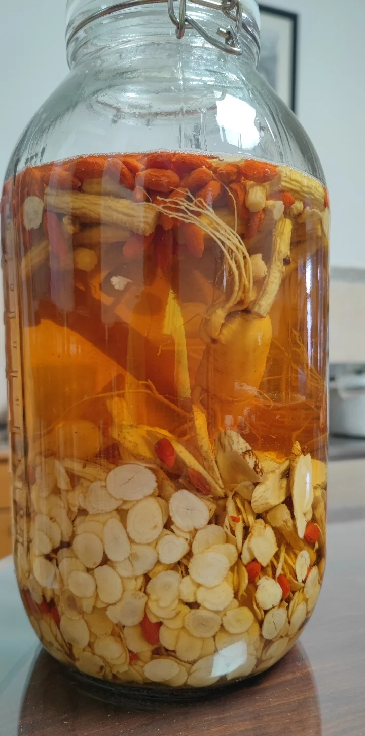 海马人参鹿茸泡酒实物展示：透明玻璃酒坛中浸泡着完整海马、人参、鹿茸片和枸杞的琥珀色药酒_1