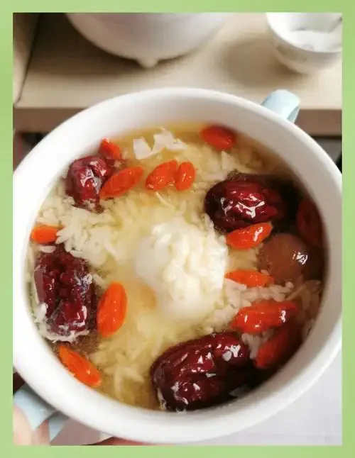 一碗热气腾腾的家常糯米酒煮鸡蛋，酒汤清亮，蛋花细腻，配有红枣和枸杞。_1