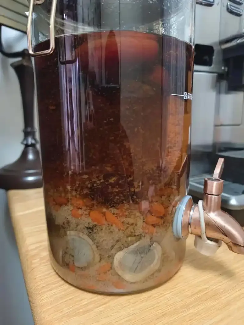 专业泡制的鹿鞭酒展示：透明酒罐中鹿鞭、枸杞、人参等原料清晰可见，琥珀色酒液透亮。_1