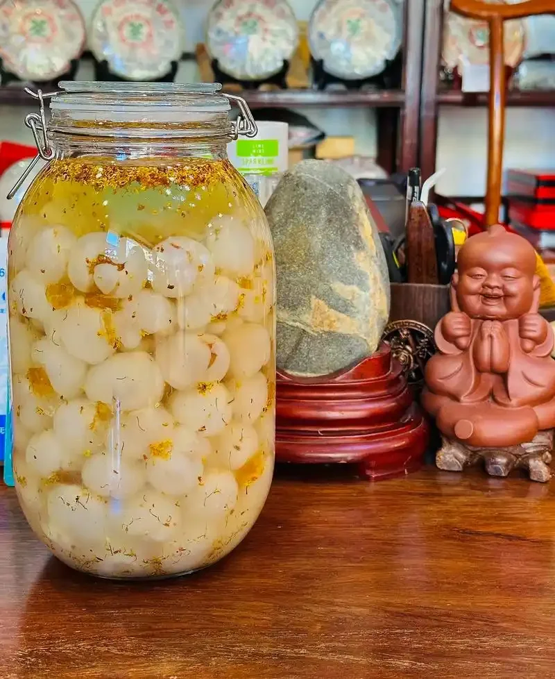 透明玻璃罐中正在浸泡的桂花果酒特写，金黄的桂花果粒在琥珀色酒液中清晰可见。_1