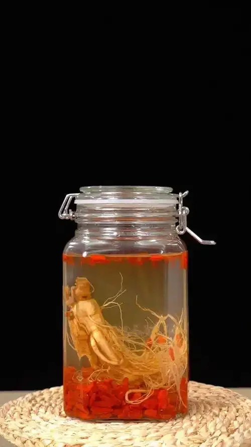 人参和牛大力在透明玻璃酒坛中浸泡的养生药酒特写_1