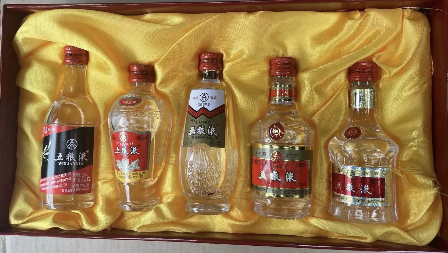 摆放着各品牌经典小酒版的木质收藏架特写，展示微缩白酒的精致与多样性。_1