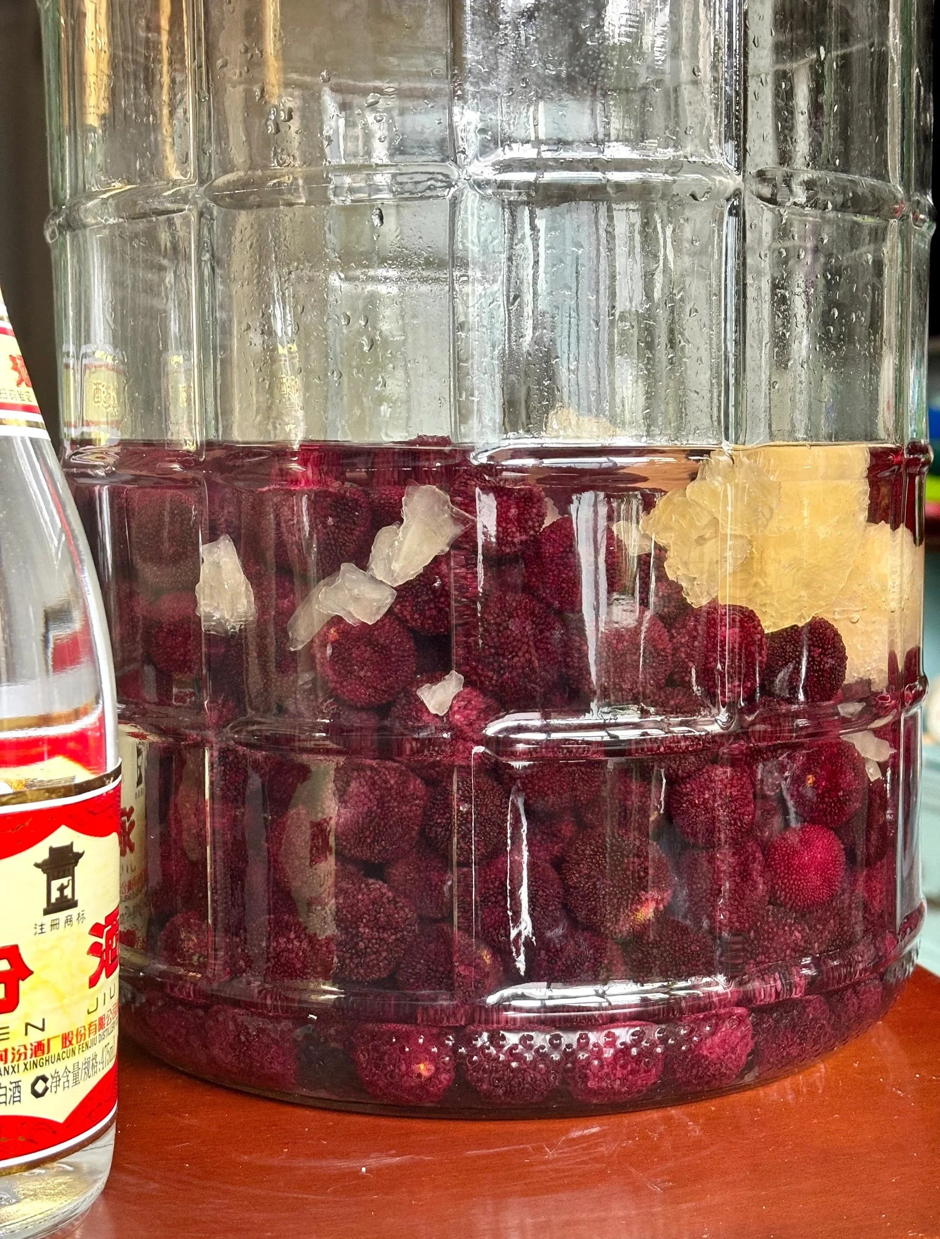 一碗泡过酒的深紫色杨梅特写，旁边配有木勺和新鲜薄荷叶，展示酿酒剩余杨梅的再利用潜力。_1