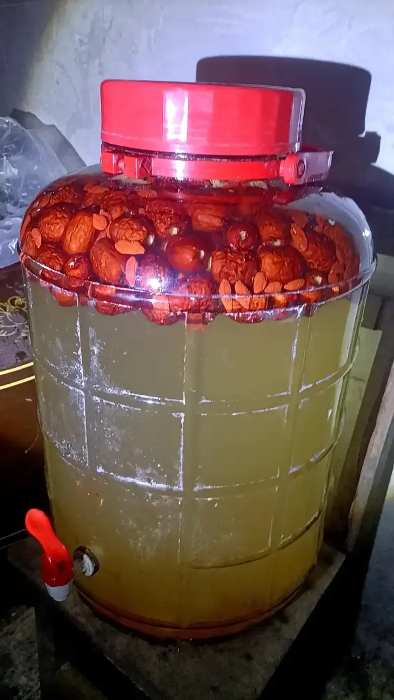 自制红枣泡酒成品展示：透明玻璃瓶中浸泡着饱满的红枣，酒液呈现清澈的琥珀色。_1