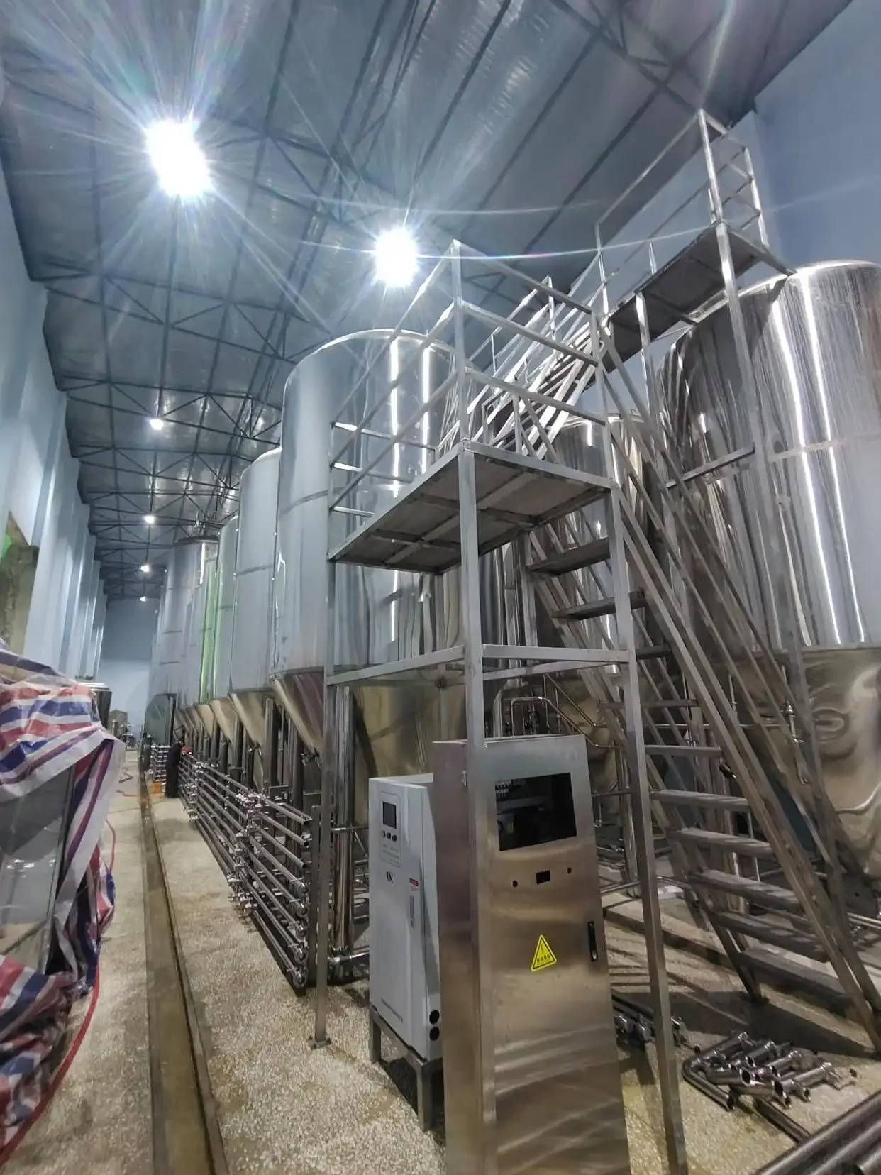 酿酒师正在操作小型自酿啤酒设备，检查温度并观察糖化过程，背景为酿造原料和工具。_1