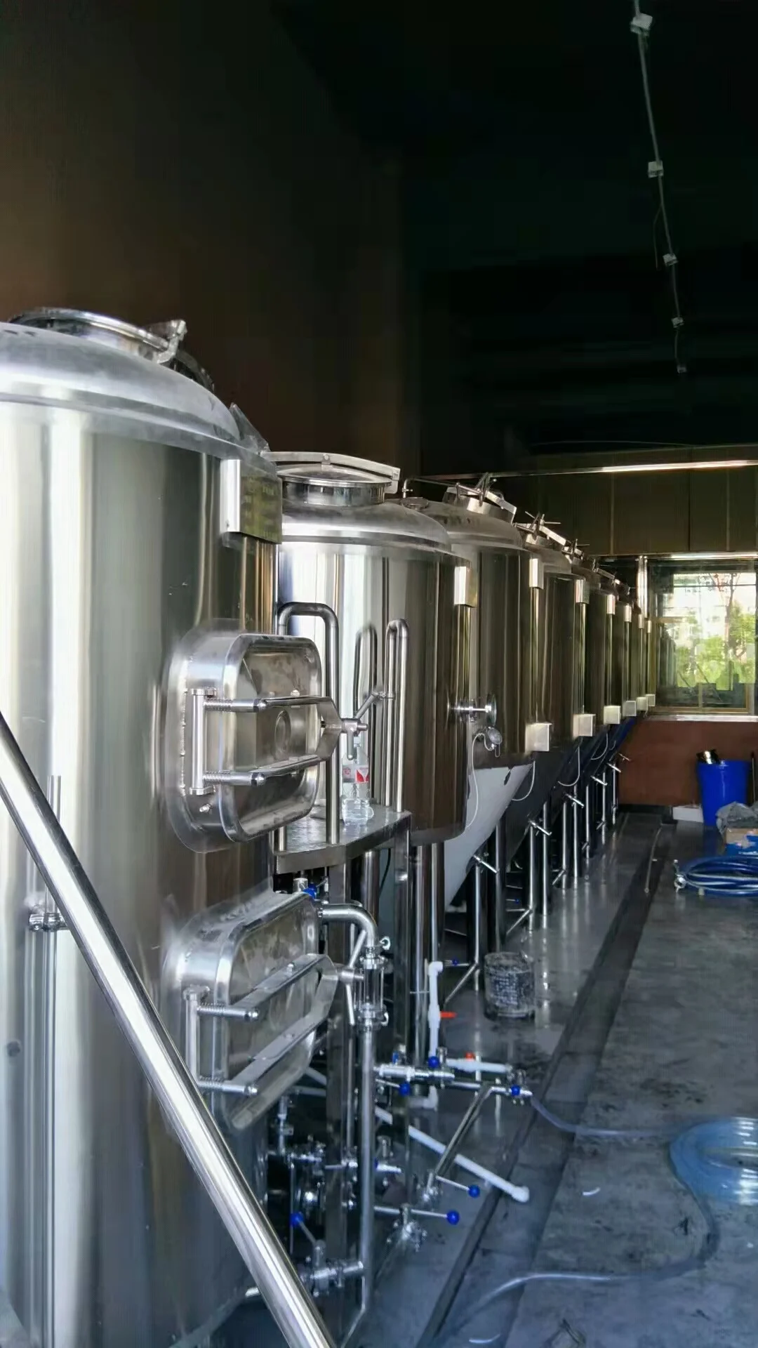 精酿啤酒厂专业酿酒师在大型不锈钢酿造设备前进行检查工作_1