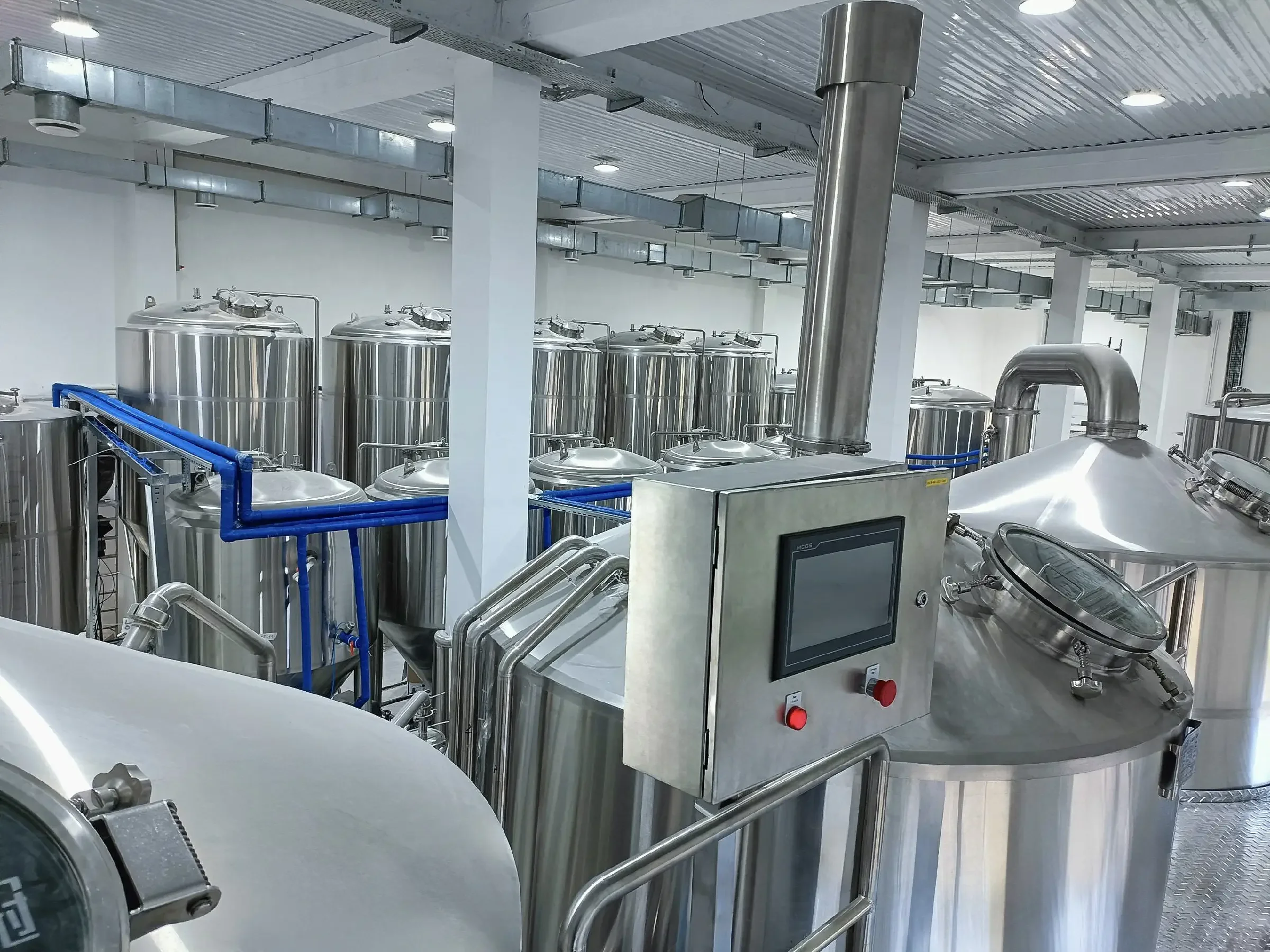 精酿啤酒坊内部糖化与发酵设备展示：不锈钢糖化锅、发酵罐及连接管线。_1