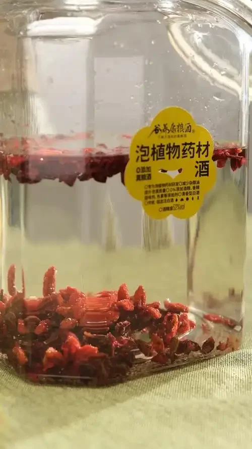 山茱萸泡酒过程展示：玻璃罐中红润的山茱萸浸泡在琥珀色酒液中，旁边配有冰糖、小秤和写有技巧的便签。_1