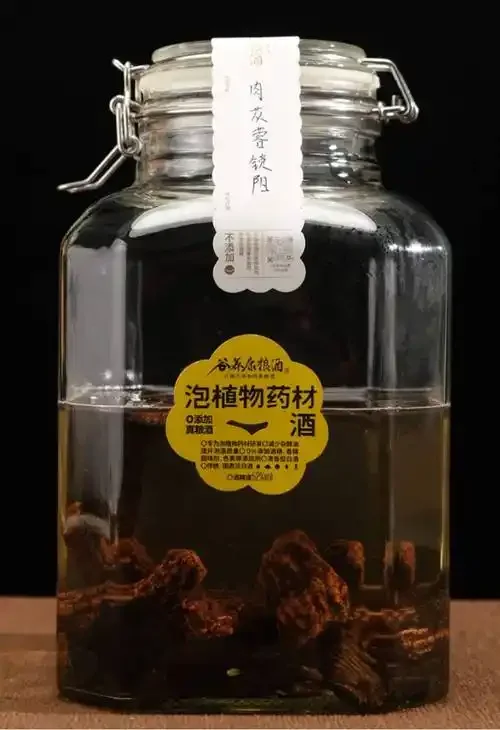 鹰骨泡酒配方药材展示：透明玻璃泡酒瓶内装有鹰骨、枸杞、红枣、当归、黄芪等中药材，整齐摆放在木桌上。_1