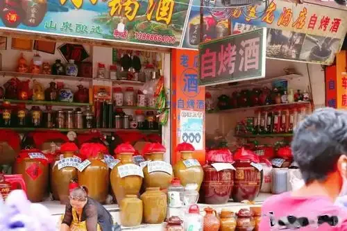 云南乡村传统酿酒场景：老师傅正用木瓢从土灶小锅蒸馏器中接取刚酿出的自烤酒_1