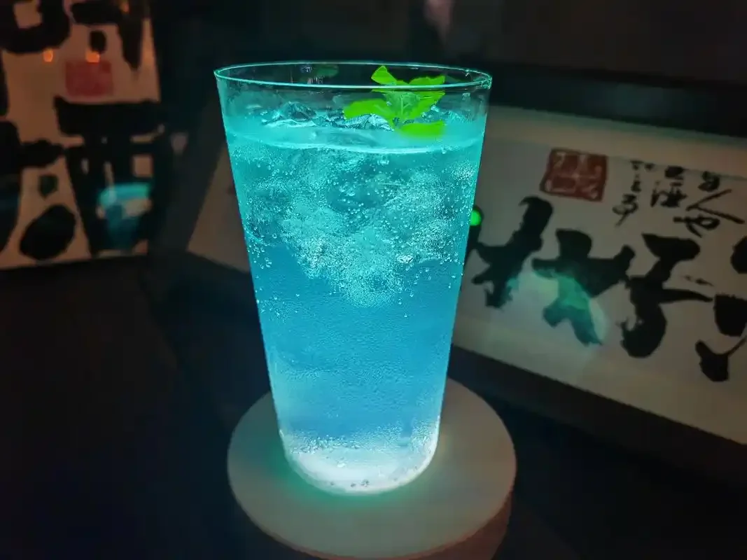 经典莫吉托鸡尾酒特写，背景有白朗姆酒瓶和新鲜青柠，展现清爽夏日调酒风情_1