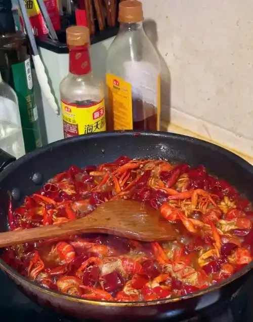 一盘刚出锅的啤酒龙虾，色泽红亮诱人，汤汁浓郁，旁边配有一杯啤酒。_1