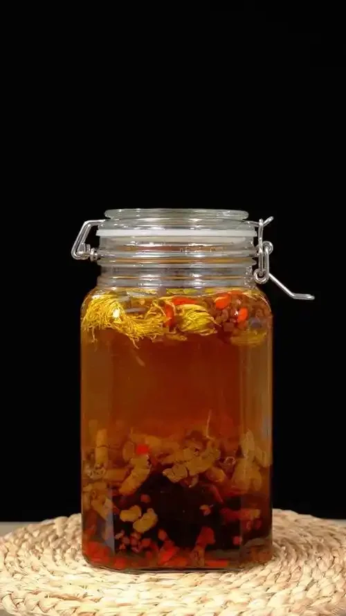 人参和牛大力一起泡酒的实物展示图，透明酒罐内清晰可见人参、牛大力、枸杞和红枣浸泡在酒中。_1