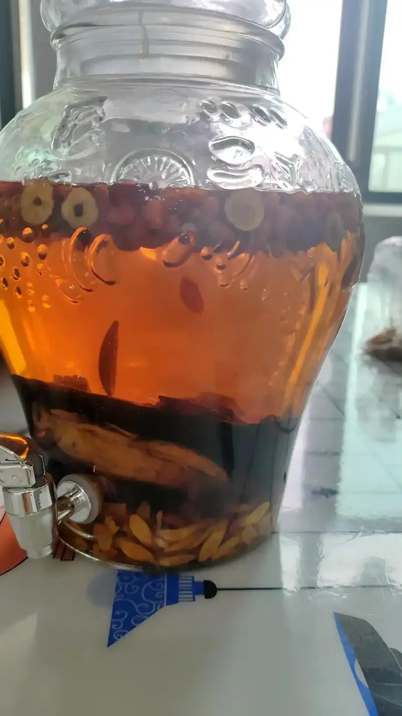家庭自制灵芝黄芪枸杞泡酒，透明玻璃罐中清晰可见药材与琥珀色酒液_1