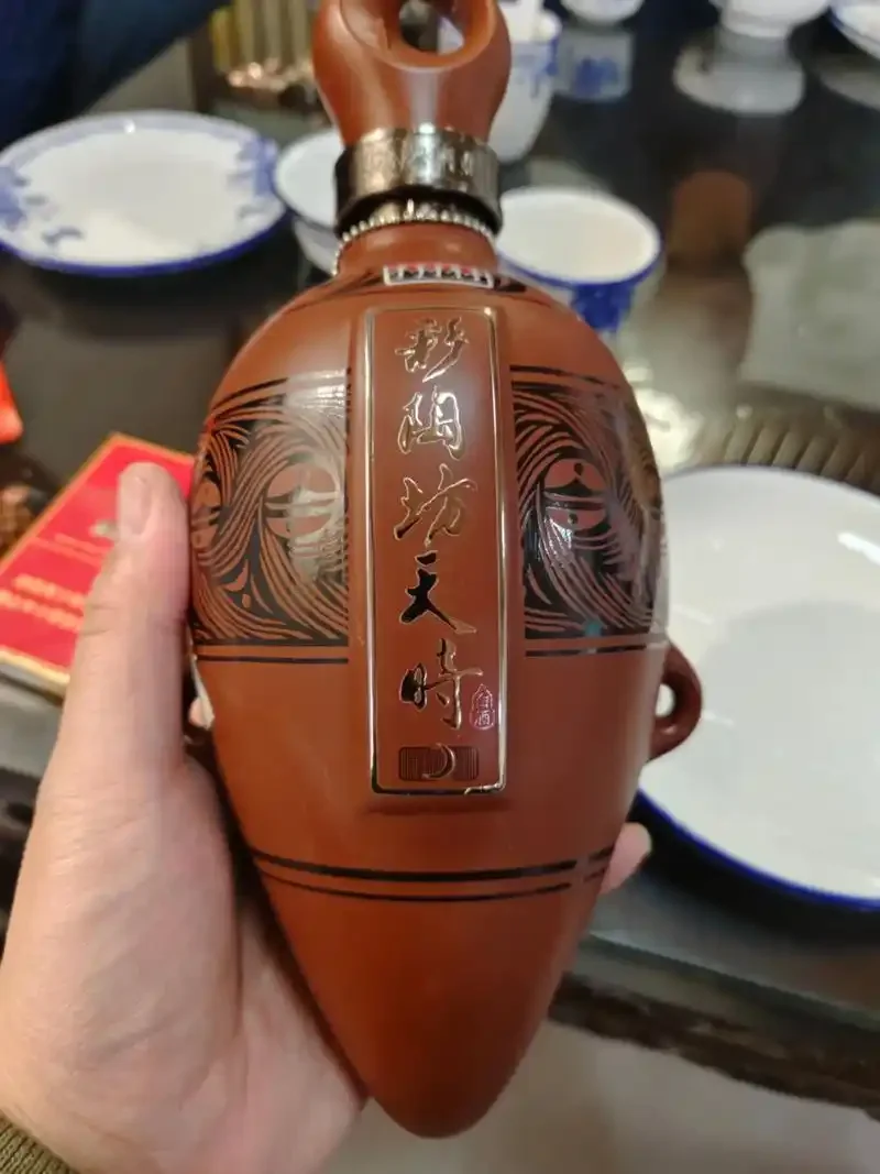 一瓶河南十字坡酒与酒盅、粮食静物展示，体现其纯粮酿造的文化底蕴。_1