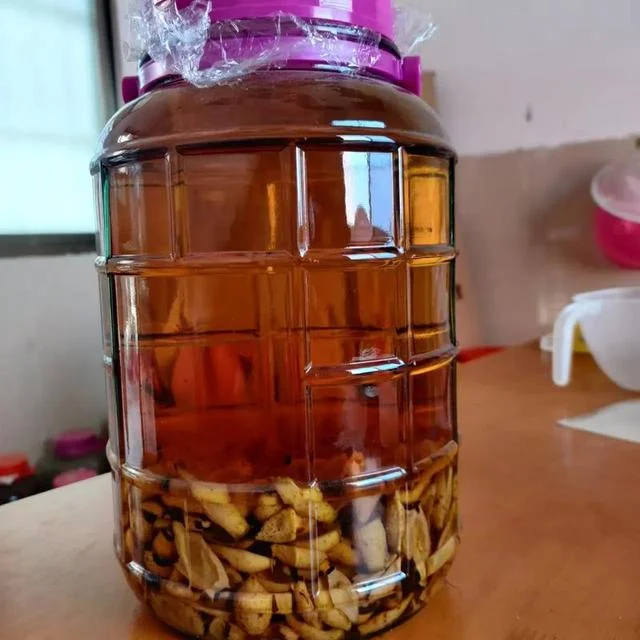 传统玻璃罐中浸泡的琥珀色首乌补肾酒，清晰可见何首乌片、枸杞、红枣等中药材，置于木质台面，展现中药养生酒的真实制作场景。_1